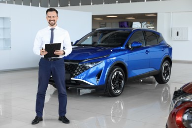 Photo of Happy salesman near new blue car in salon