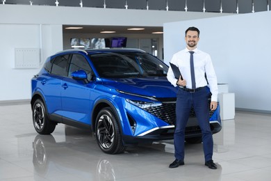 Photo of Happy salesman near new blue car in salon