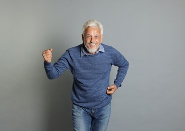 Portrait of happy senior man on grey background