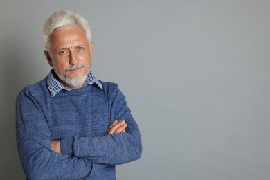 Portrait of senior man on grey background, space for text