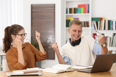 Photo of Preparing for exam. Cheerful students with laptop at table indoors