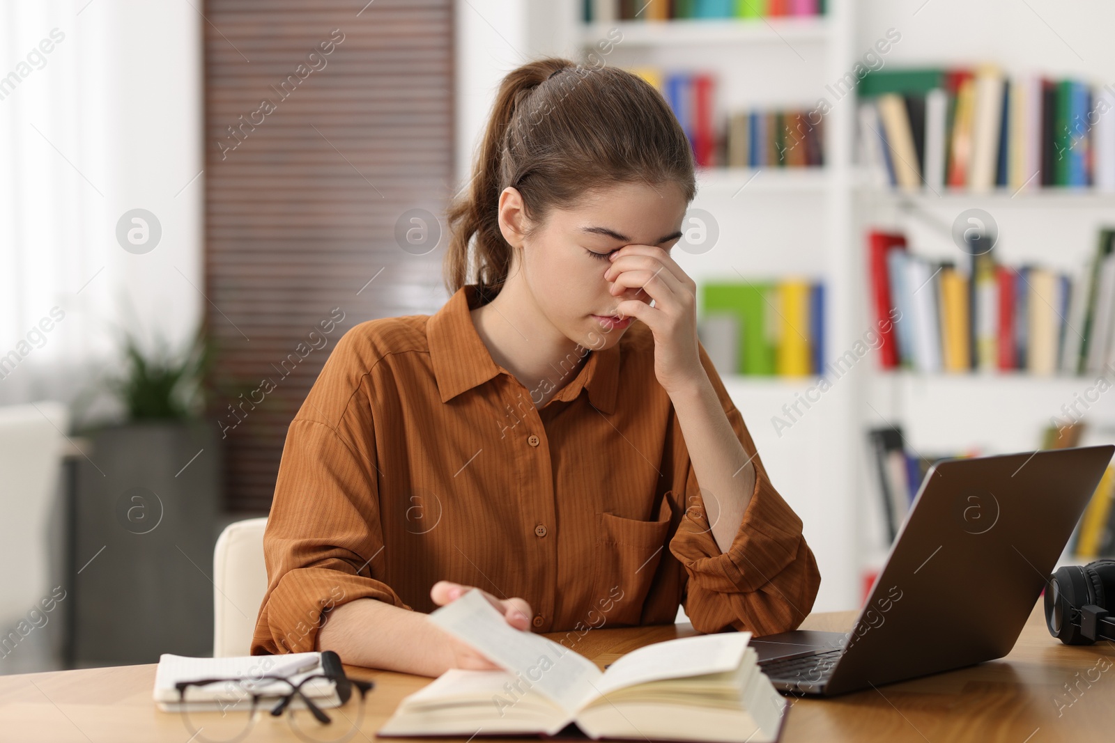 Photo of Tired student preparing for exam at table indoors