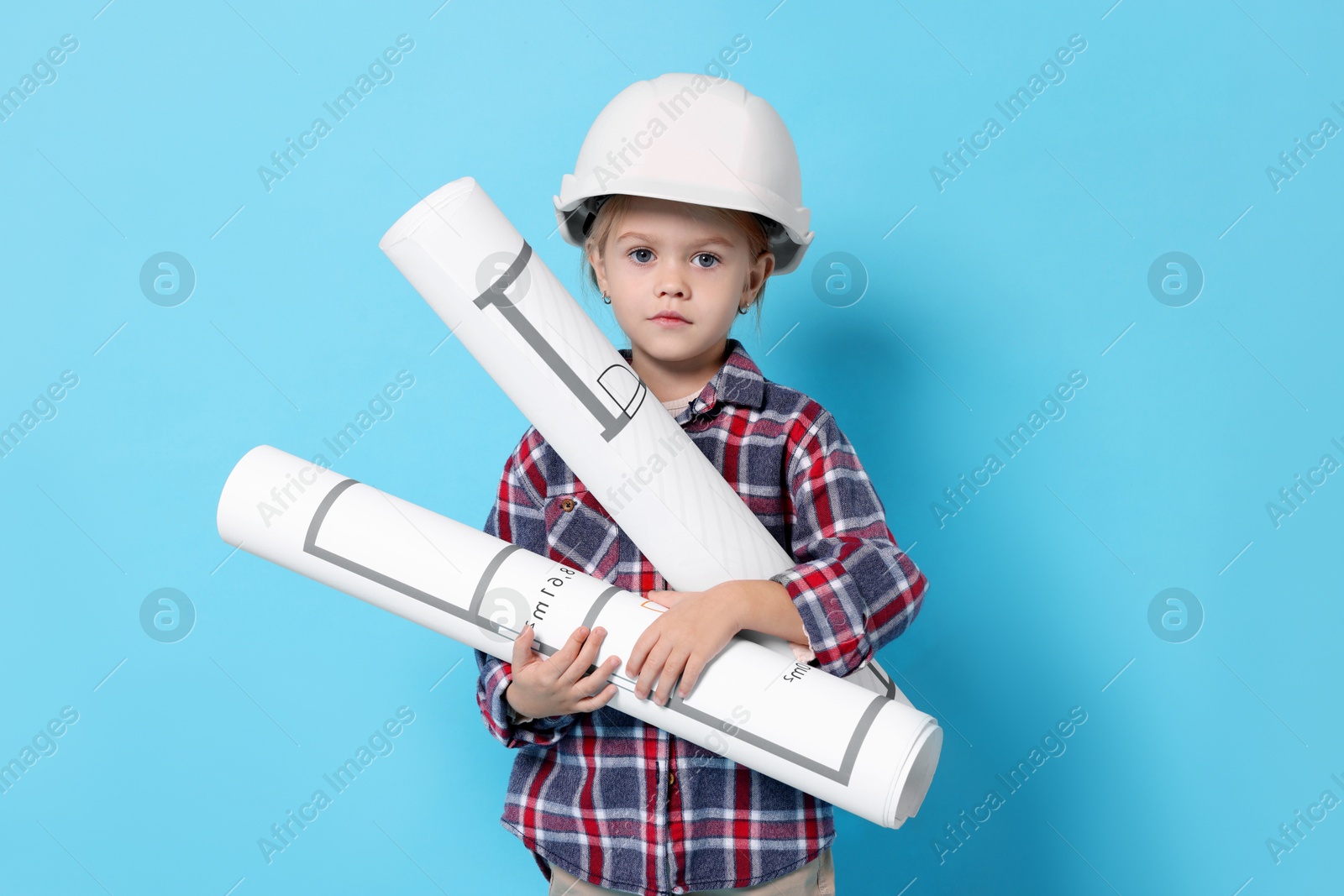 Photo of Little girl with house plan pretending to be architect on light blue background. Dreaming of future profession