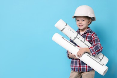 Photo of Little girl with house plan pretending to be architect on light blue background, space for text. Dreaming of future profession