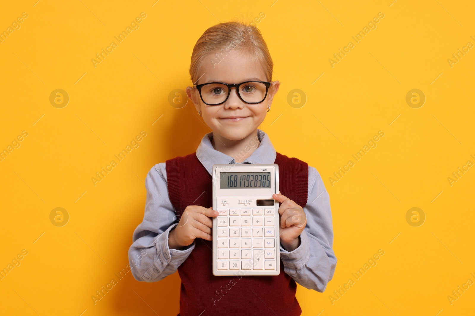 Photo of Little girl with calculator pretending to be accountant on orange background. Dreaming of future profession