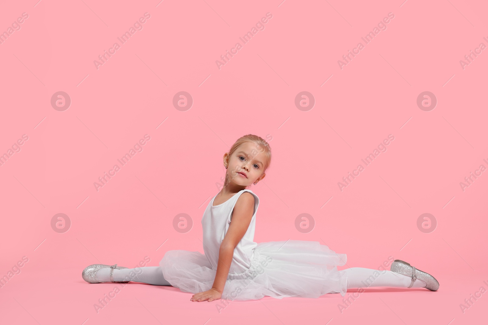 Photo of Little girl pretending to be ballerina on pink background. Dreaming of future profession