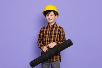 Photo of Boy with blueprint tube pretending to be architect on violet background. Dreaming of future profession