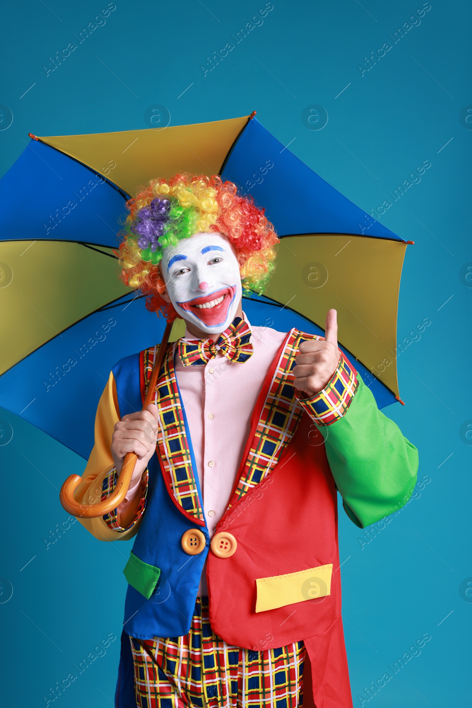 Photo of Clown with colorful umbrella on blue background