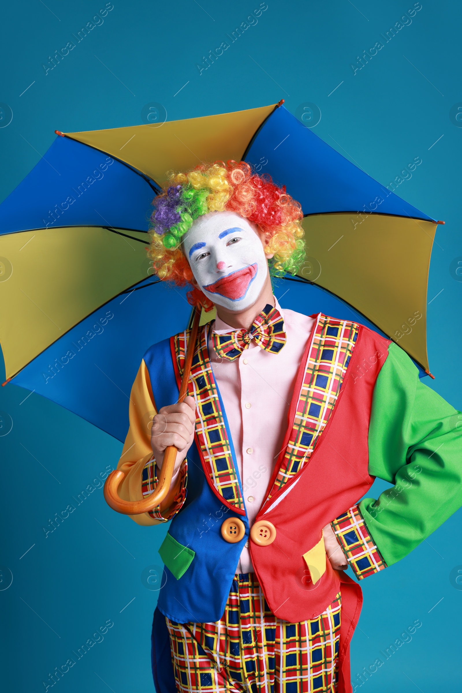 Photo of Clown with colorful umbrella on blue background