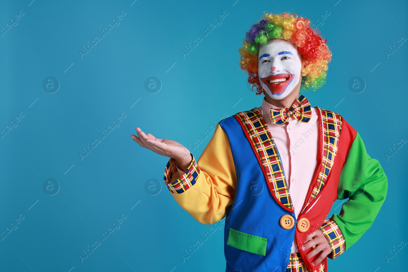 Photo of Portrait of happy clown on blue background, space for text