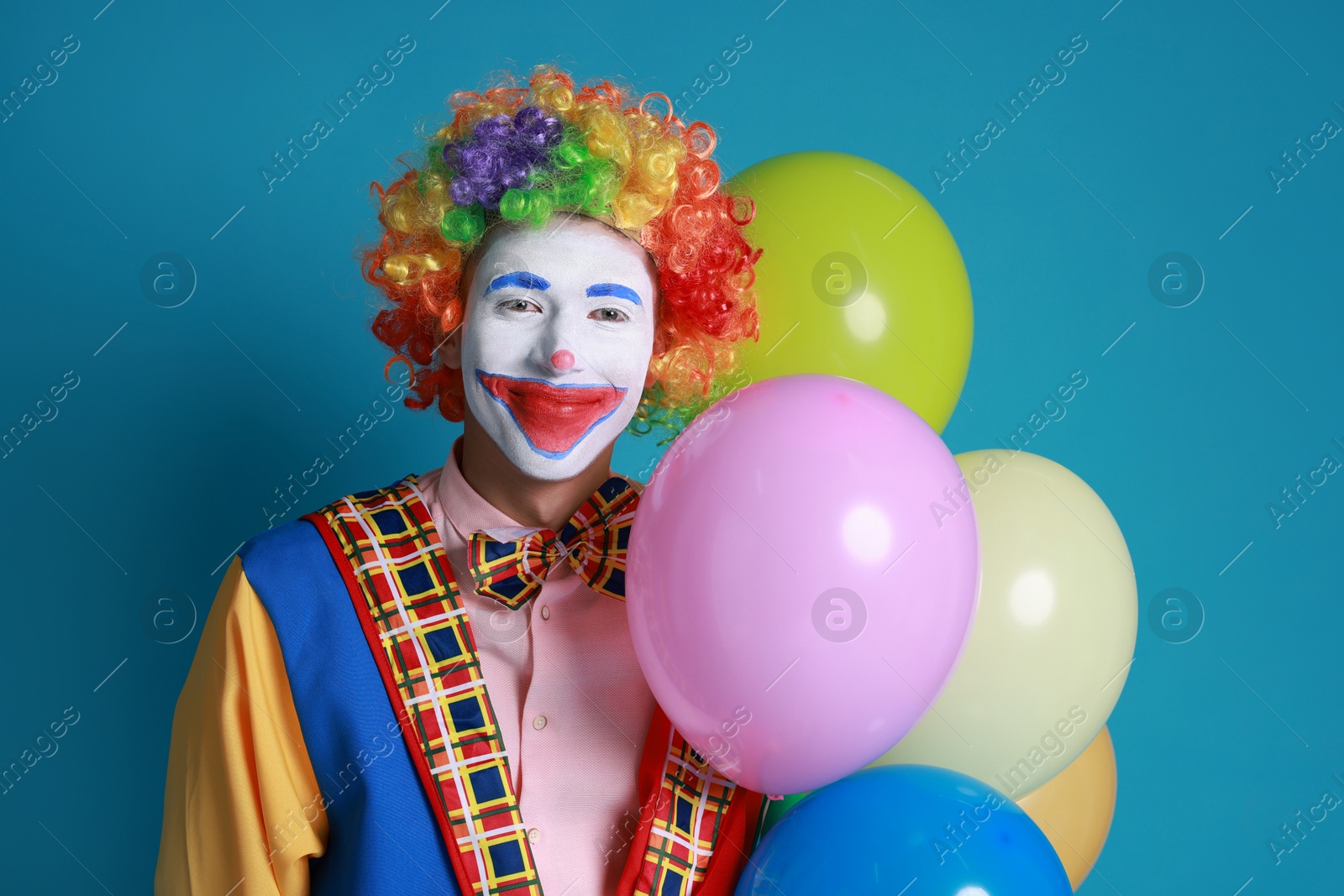 Photo of Smiling clown with colorful balloons on blue background