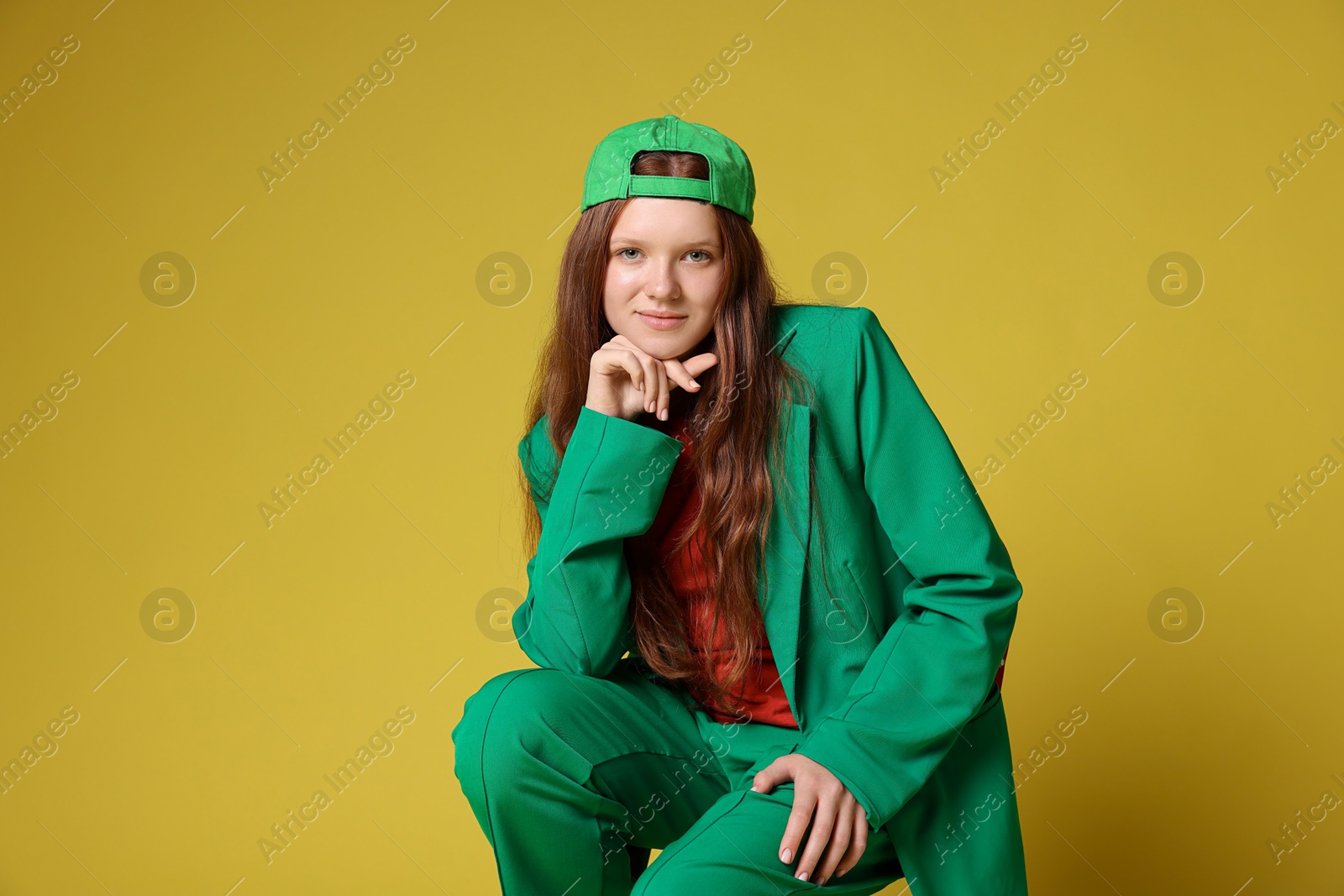 Photo of Fashion portrait of red-haired teenage girl on golden background