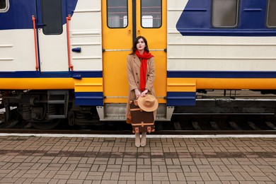 Photo of Woman with suitcase near train on platform of railway station