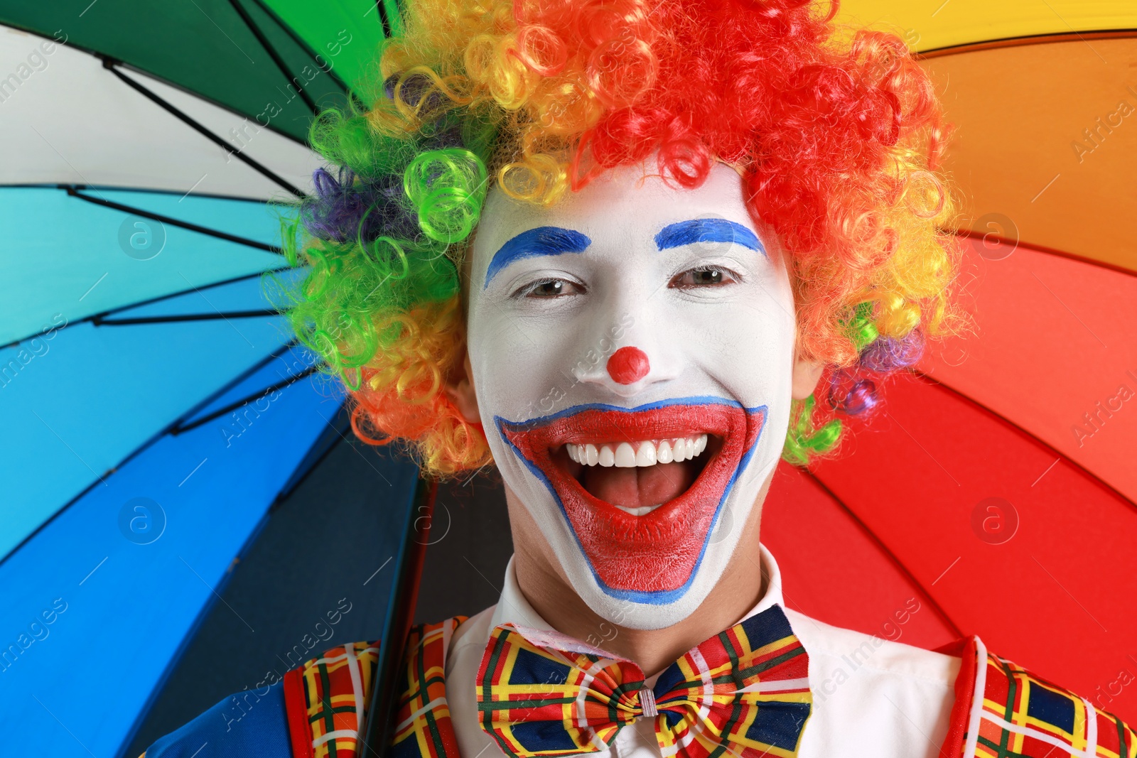 Photo of Portrait of happy clown with colorful umbrella