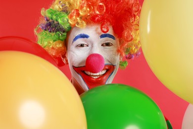 Photo of Happy clown with colorful balloons on red background