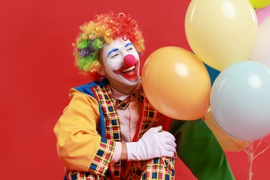 Photo of Happy clown with colorful balloons on red background