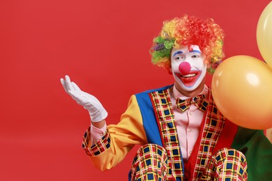 Photo of Happy clown with colorful balloons on red background