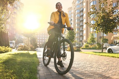 Photo of Smiling woman with bicycle outdoors on sunny day, low angle view