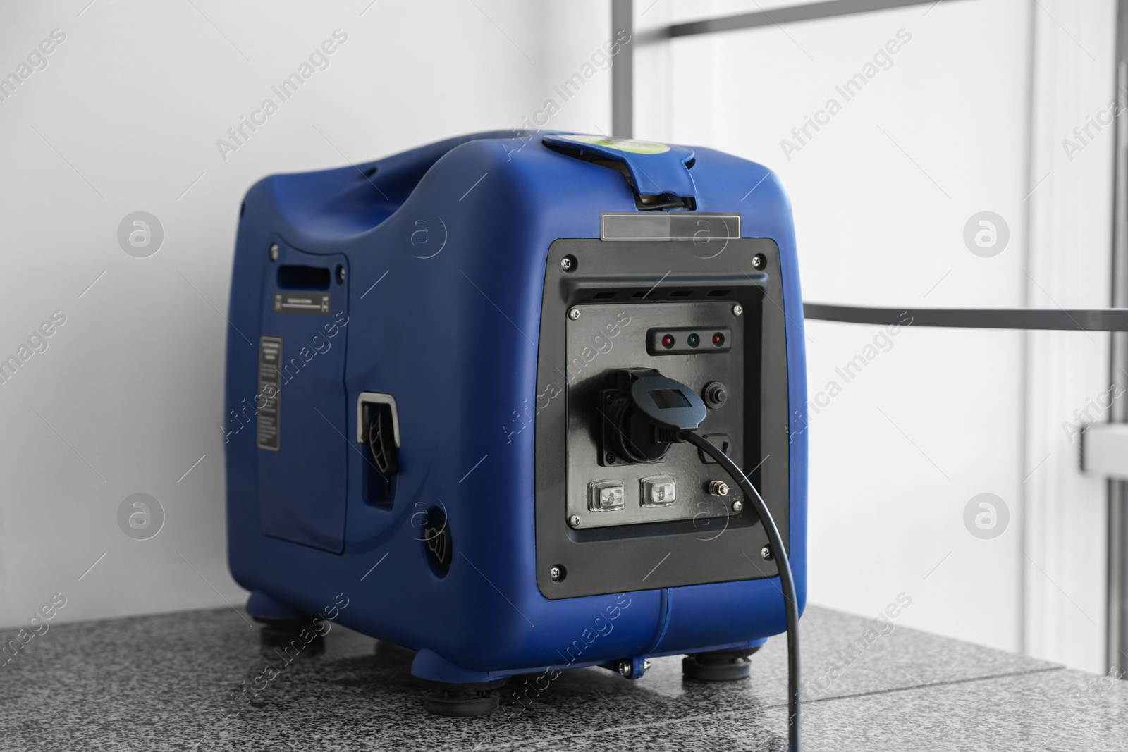 Photo of Modern portable power station near beige wall indoors