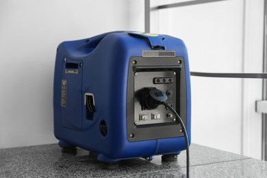 Photo of Modern portable power station near beige wall indoors