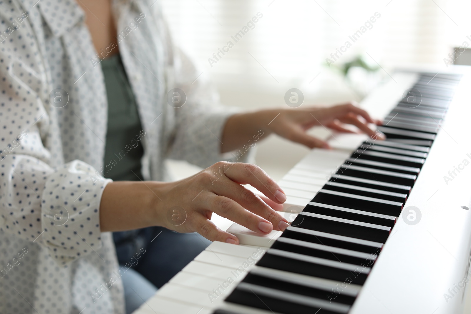 Photo of Woman playing synthesizer indoors, closeup. Electronic musical instrument