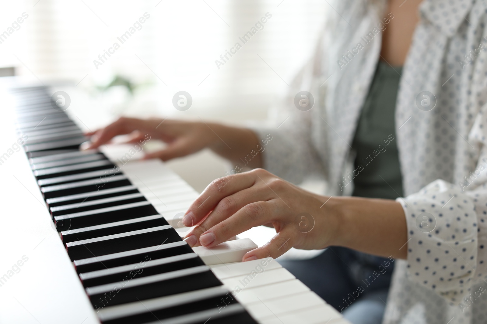 Photo of Woman playing synthesizer indoors, closeup. Electronic musical instrument