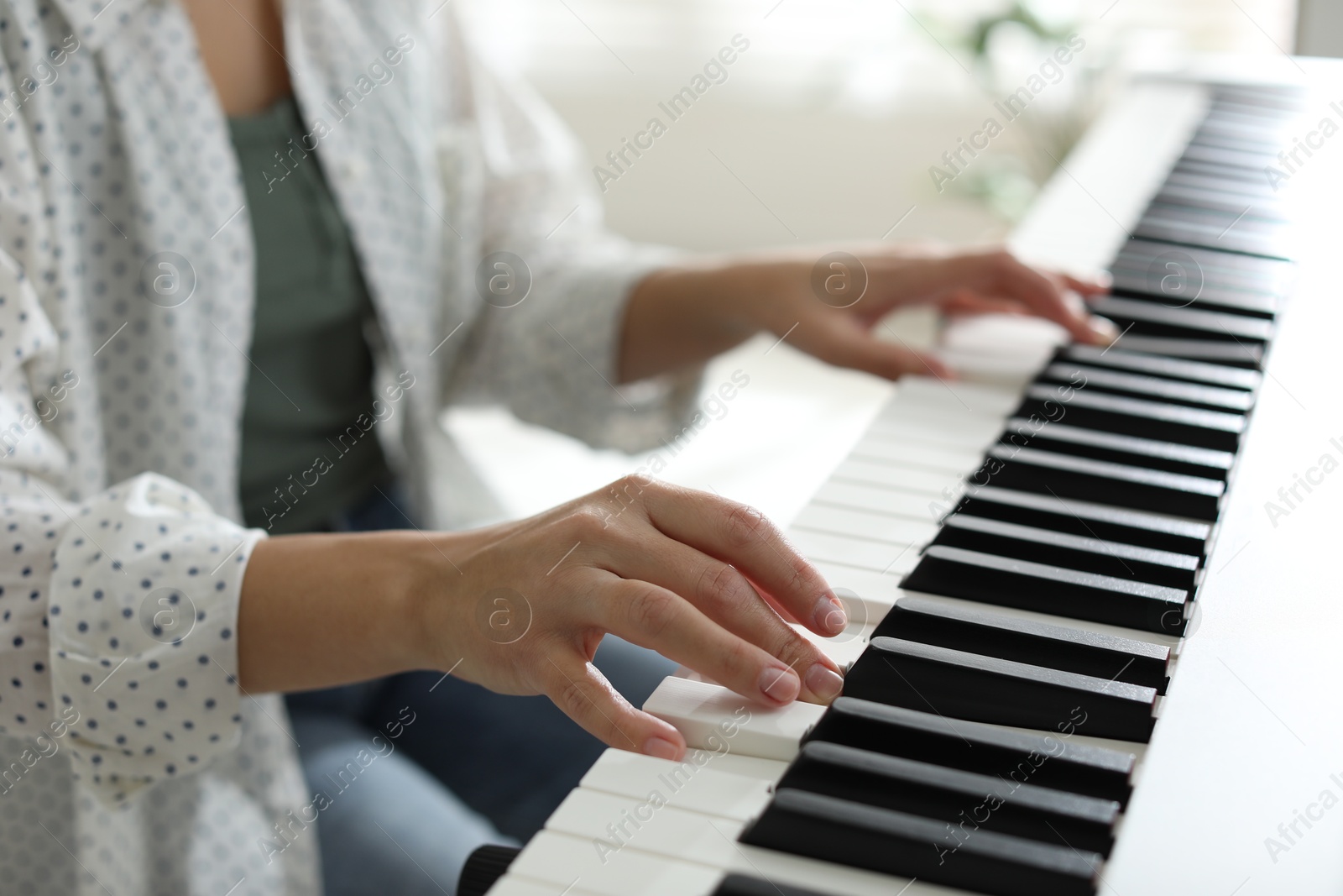 Photo of Woman playing synthesizer indoors, closeup. Electronic musical instrument