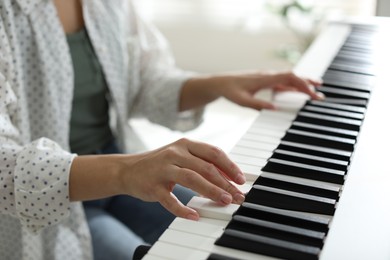 Photo of Woman playing synthesizer indoors, closeup. Electronic musical instrument