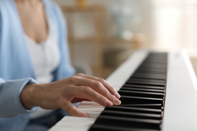 Photo of Woman playing synthesizer indoors, closeup. Electronic musical instrument