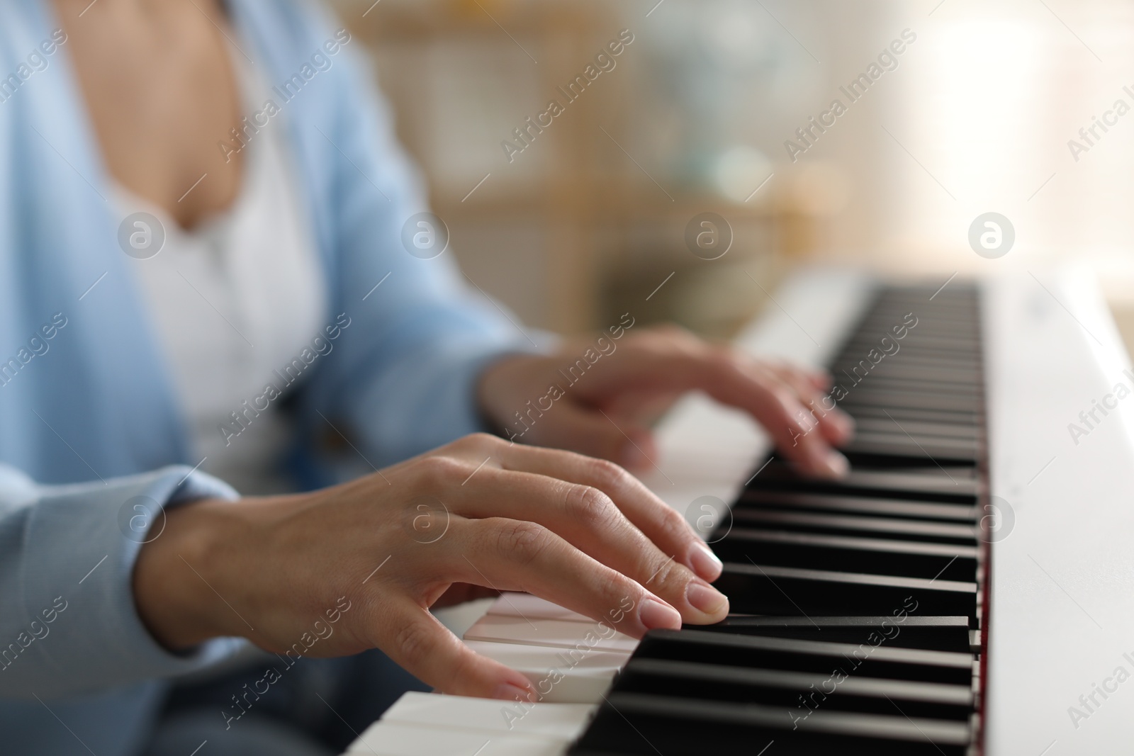 Photo of Woman playing synthesizer indoors, closeup. Electronic musical instrument