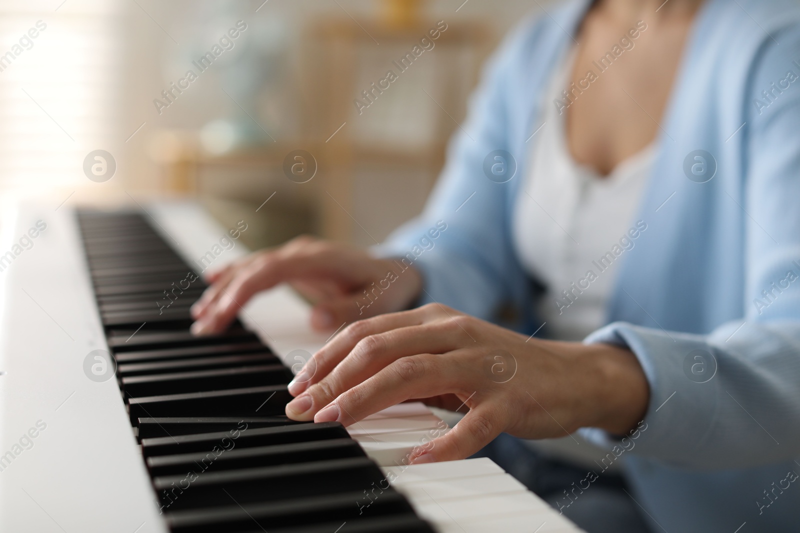 Photo of Woman playing synthesizer indoors, closeup. Electronic musical instrument