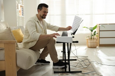 Photo of Smiling man playing synthesizer at home. Electronic musical instrument