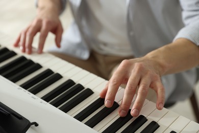 Photo of Man playing synthesizer indoors, closeup. Electronic musical instrument