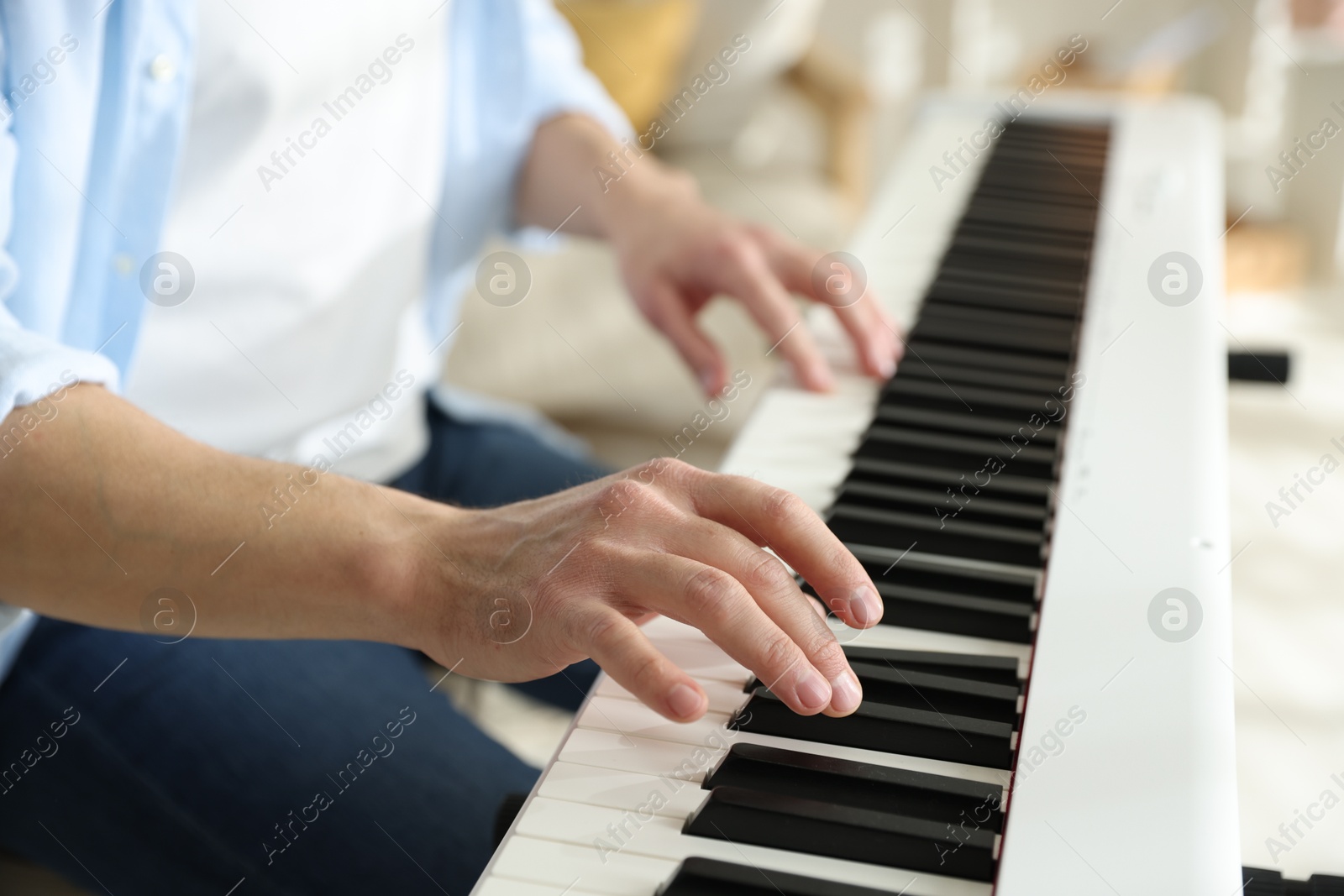 Photo of Man playing synthesizer indoors, closeup. Electronic musical instrument