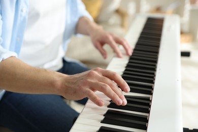 Photo of Man playing synthesizer indoors, closeup. Electronic musical instrument