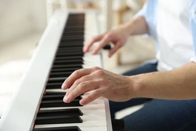 Photo of Man playing synthesizer indoors, closeup. Electronic musical instrument