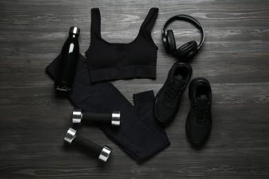 Photo of Flat lay composition with black sportswear and sneakers on wooden background