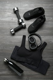 Photo of Flat lay composition with black sportswear and sneakers on wooden background