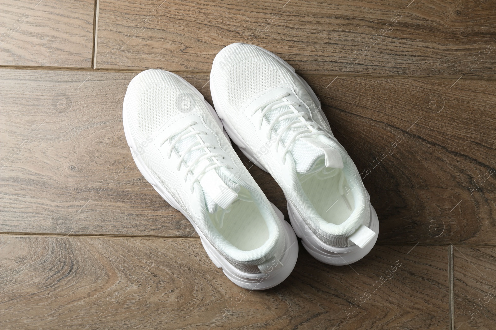 Photo of Pair of stylish white sneakers on wooden background, top view