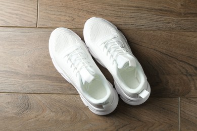 Photo of Pair of stylish white sneakers on wooden background, top view