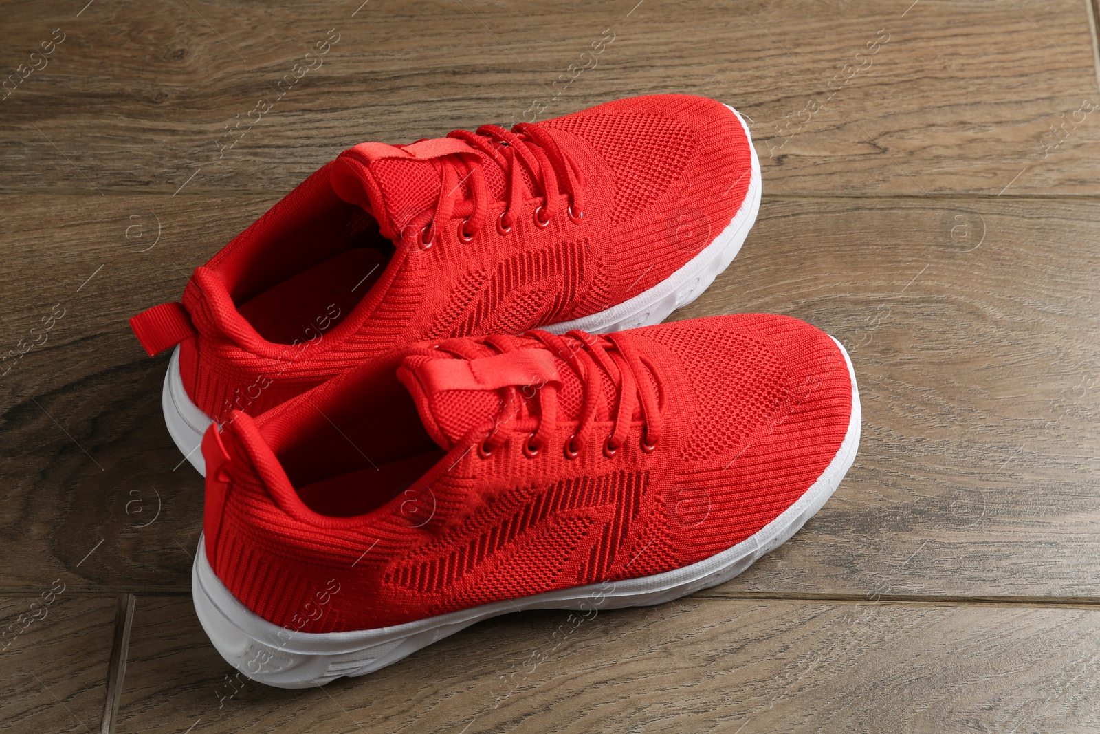 Photo of Pair of stylish red sneakers on wooden background