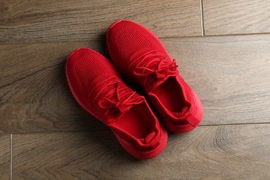 Photo of Pair of stylish red sneakers on wooden background, top view