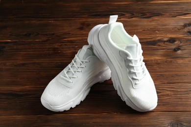 Photo of Pair of stylish white sneakers on wooden background