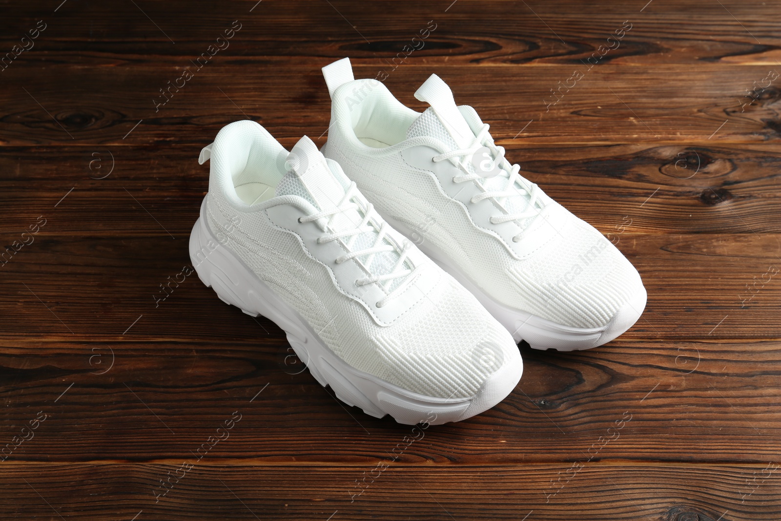 Photo of Pair of stylish white sneakers on wooden background