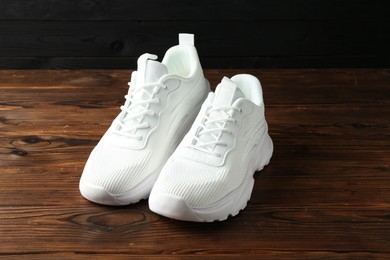 Photo of Pair of stylish white sneakers on wooden background