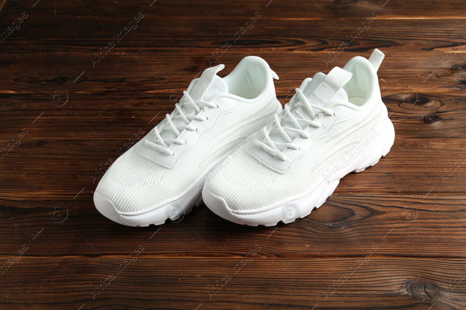 Photo of Pair of stylish white sneakers on wooden background