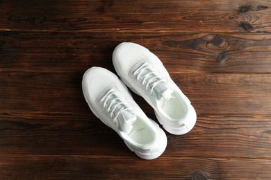 Photo of Pair of stylish white sneakers on wooden background, top view