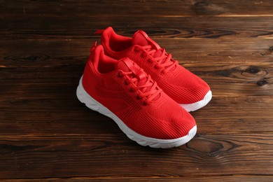 Photo of Pair of stylish red sneakers on wooden background