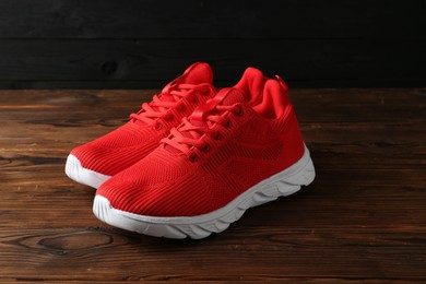 Photo of Pair of stylish red sneakers on wooden background