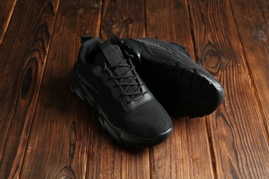 Photo of Pair of stylish black sneakers on wooden background